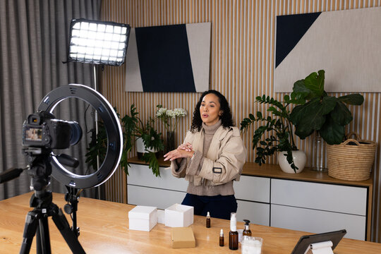 African American woman demoing skincare and applying cream at home studio with ring light and DSLR
