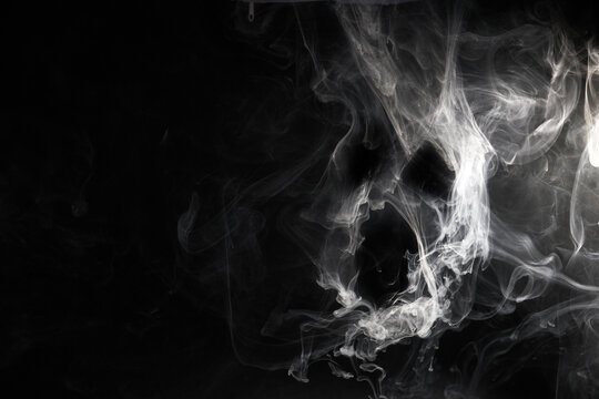 White smoke forming abstract skull face on black background