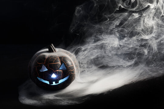 Halloween pumpkin glowing with blue light and smoke