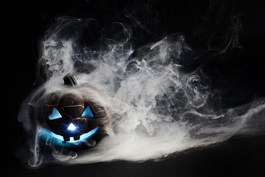 Glowing jack-o-lantern surrounded by eerie blue smoke on halloween night