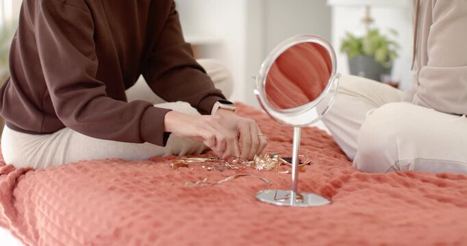Diverse women friends sorting jewels on bed, reacting as friend coming with dresses for styling