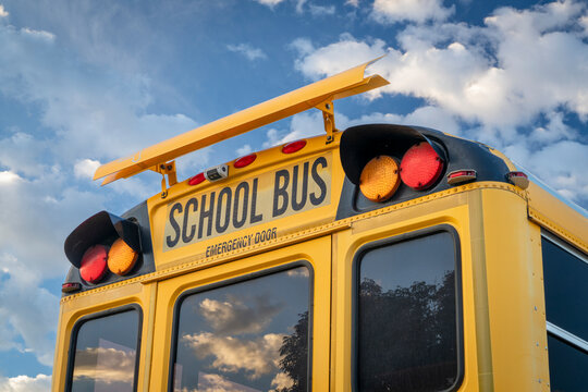 rear end of a yellow shcool bus with wraning lights and emergency exit door