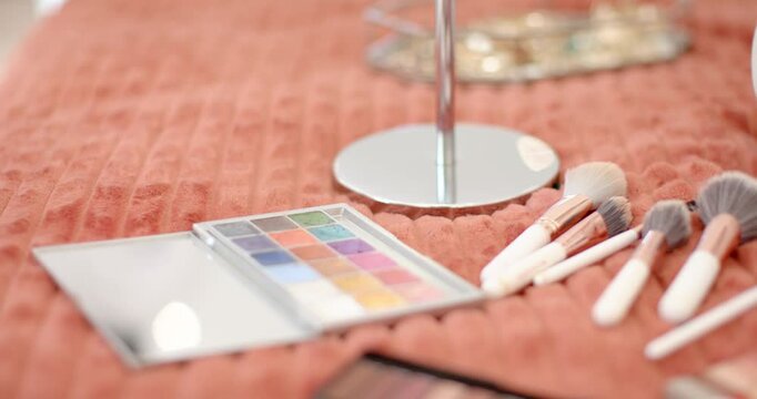 Camera is pulling focus and shifting right, revealing makeup brushes and palettes for beauty prep