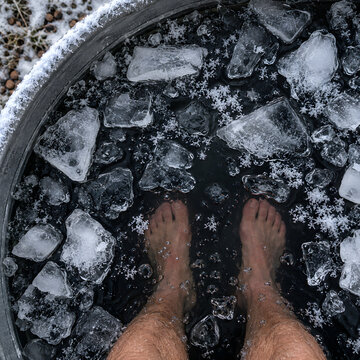 Top View of Ice Cubes Floating in Dark Cold Plunge Water with Feet