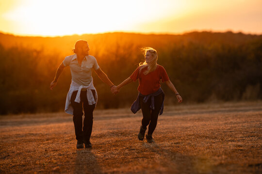 Couple running hand in hand during golden hour sunset