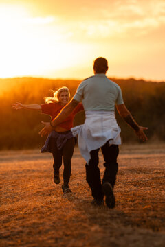 Happy couple running to embrace at sunset outdoors