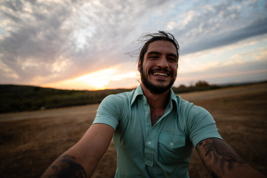 Happy man smiling with tattoos at sunset