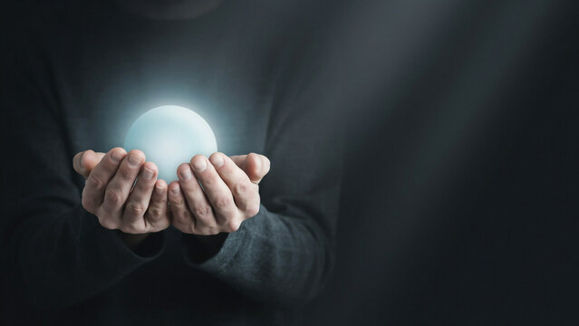 Hands gently holding a luminous orb with soft light