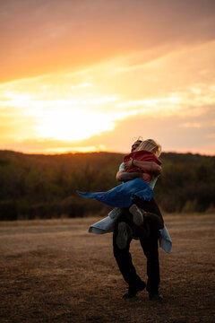Couple embracing joyfully at sunset in a field