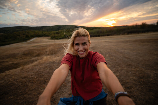 Blonde woman smiling, enjoying sunset outdoors