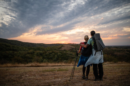 Couple hiking enjoying beautiful sunset on mountain trail