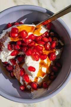 light purple cafe bowl with greek yogurt, pomegranate arils and pomegranate molasses drizzle