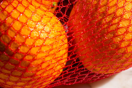 close up of orange fruit in red mesh, net bag