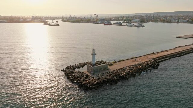 Varna sea lighthouse breakwater pier aerial drone view sun glare sunset Black Sea port Bulgaria landscape footage
