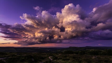 Obraz premium Vast clouds glow purple and gold at dusk. Distant hills stretch beneath the sky's vivid hues. Sunset paints the horizon in soft, fading light. The scene evokes calm, mystery, and awe