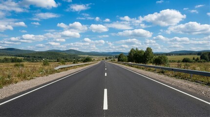 Obraz premium Asphalt road stretches straight ahead under bright blue sky. White dashed lines guide drivers through open countryside. Clouds drift lazily above distant hills and green fields