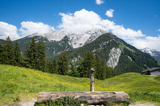 H&ouml;lzerner Brunnen mit Wassertrog auf der Litzlalm vor dem Bergpanorama.