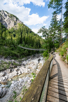 Holzsteg und Wanderweg zur Klausbachtal-H&auml;ngebr&uuml;cke im Hochformat.