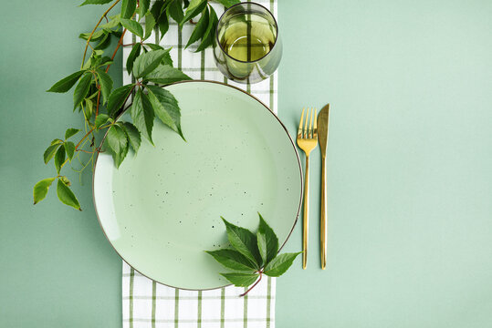 Elegant Thanksgiving Table Setting with Greenery and Golden Cutlery on Pastel Background