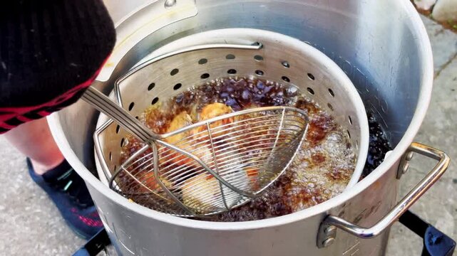 Cook Lifts Golden Chicken Wings From Deep Fryer