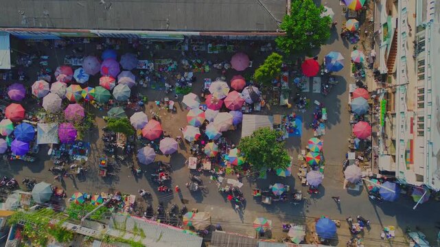 Aerial view of Pasar Pagi Pemalang market with colorful umbrellas and crowds of people shopping among stalls in Pemalang, Central Java, Indonesia.