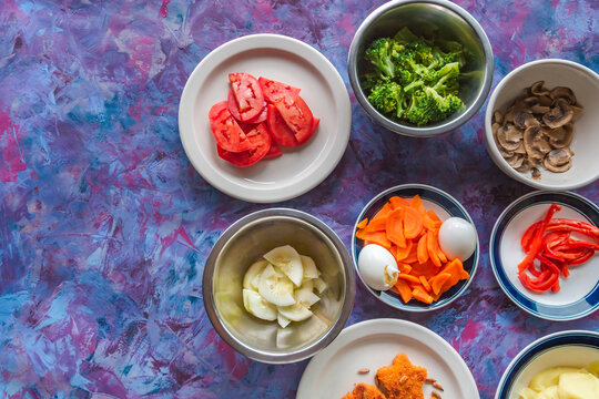 Vibrant ingredients arranged for a fresh meal. Plates hold colorful vegetables and eggs. Textures and hues suggest homemade cooking. Perfect for culinary, healthy lifestyle, or recipe content