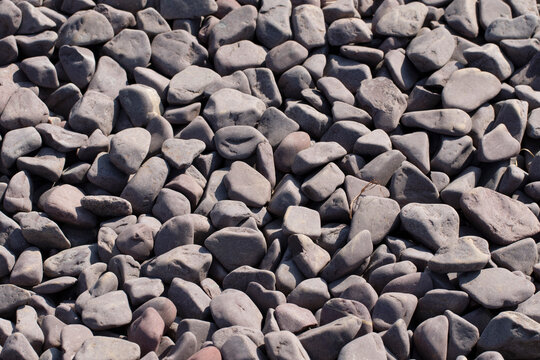 Collection of smooth, rounded river pebbles shaped by water and wind erosion, commonly composed of basalt, andesite, or dark sedimentary rocks, and used decoratively.