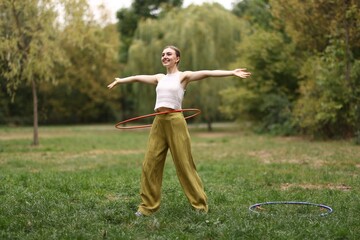Athletic young woman exercising with hula hoop in park © New Africa