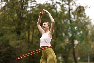 Athletic young woman exercising with hula hoop in park © New Africa
