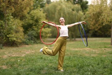Athletic young woman exercising with hula hoops in park © New Africa