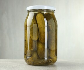 Obraz premium Pickled cucumbers in glass jar on grey table, closeup