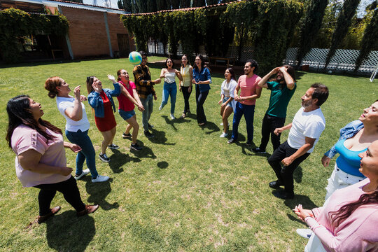 group of latin friends playing volleyball game in public park in Mexico Latin America. multicultural hispanic teamwork having fun together outdoors