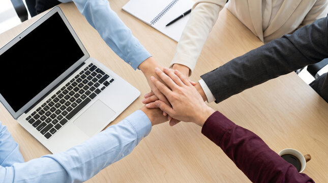 Overhead View of Business Team Stacking Hands Above a Desk