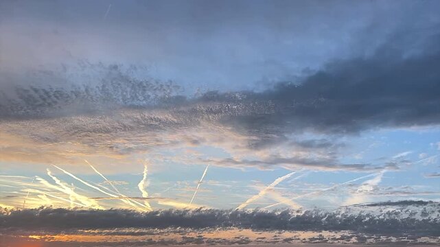 Tame Lapse of Dramatic Sunset Sky with Clouds and Airplane Contrails