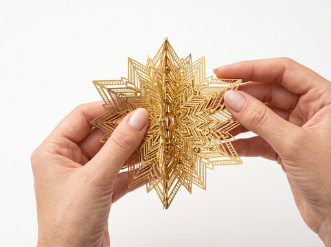 Hands holding a decorative golden metallic star ornament