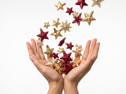 Hands holding falling Christmas star decorations on white