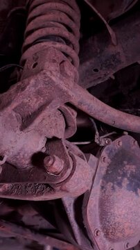 Detailed view of rusted car undercarriage, differential housing, and suspension coil spring during service.