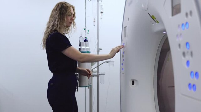Female radiology technician using the control panel of a CT scanner before a diagnostic imaging examination.
