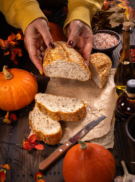 Hands tearing fresh rustic sourdough bread during autumn harvest