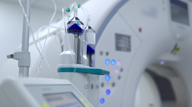 Close-up of an automatic contrast injector with a CT scanner in the background of a computed tomography room