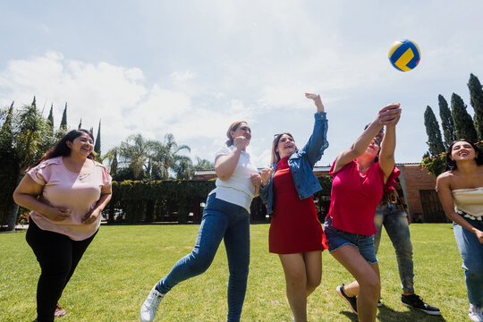 group of latin friends playing volleyball game in public park in Mexico Latin America. multicultural hispanic teamwork having fun together outdoors
