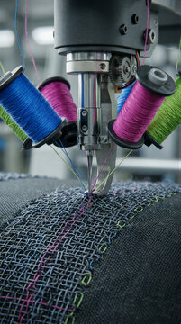 Industrial embroidery machine stitching colored threads into mesh fabric. Automated textile manufacturing. Technical fabric production and mesh processing. Precision machine operation