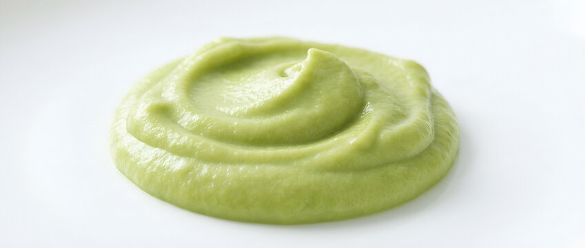 Creamy green avocado spread with swirl pattern on white surface