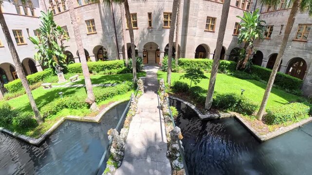 4K camera rises above a stone bridge crossing a peaceful historic courtyard pool Saint Augustine, Florida.
