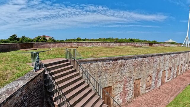 The camera rises beside a staircase to reveal grass above brick chambers.