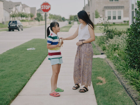 Mother talking with her daughter on a sunny suburban sidewalk