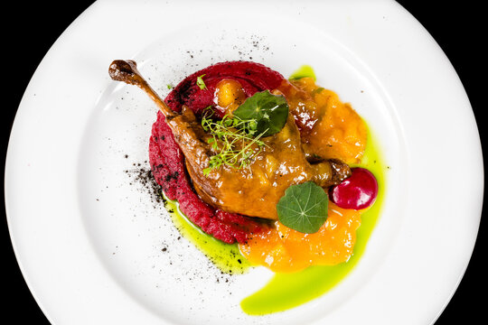 Roasted duck leg confit with vegetable puree on white plate
