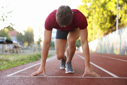 Athletic man in starting position for run at stadium