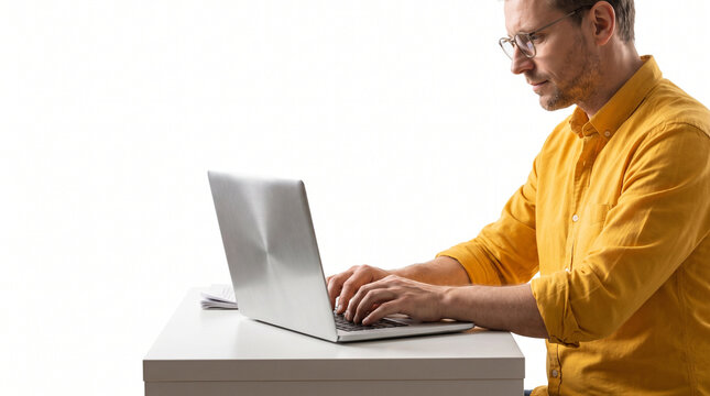 Man typing on laptop at simple desk with focused expression  