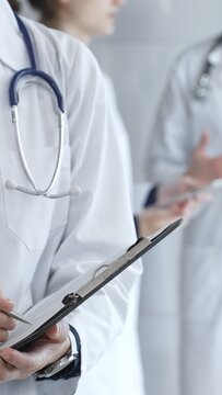 Medical professional writing on clipboard with stethoscope, a doctor and female assistant collaborating in a clinic, discussing patient data and healthcare information